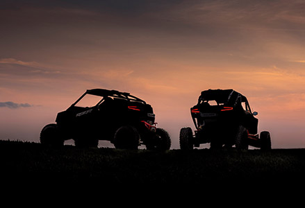 Two shadowed out RZR vehicles in the sunset