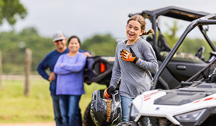 Young girl running to her Polaris RZR 200