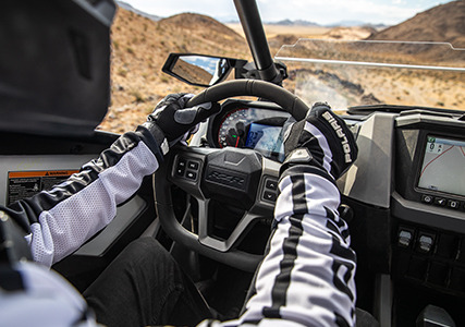 conductor que sujeta el volante dentro de la cabina de su rzr pro xp 4