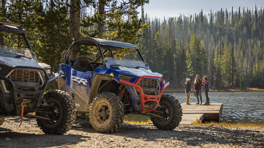 vue avant de deux RZR stationnés devant un lac