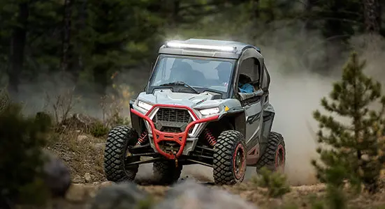 Un RZR Trail S qui roule sur un sentier dans la forêt