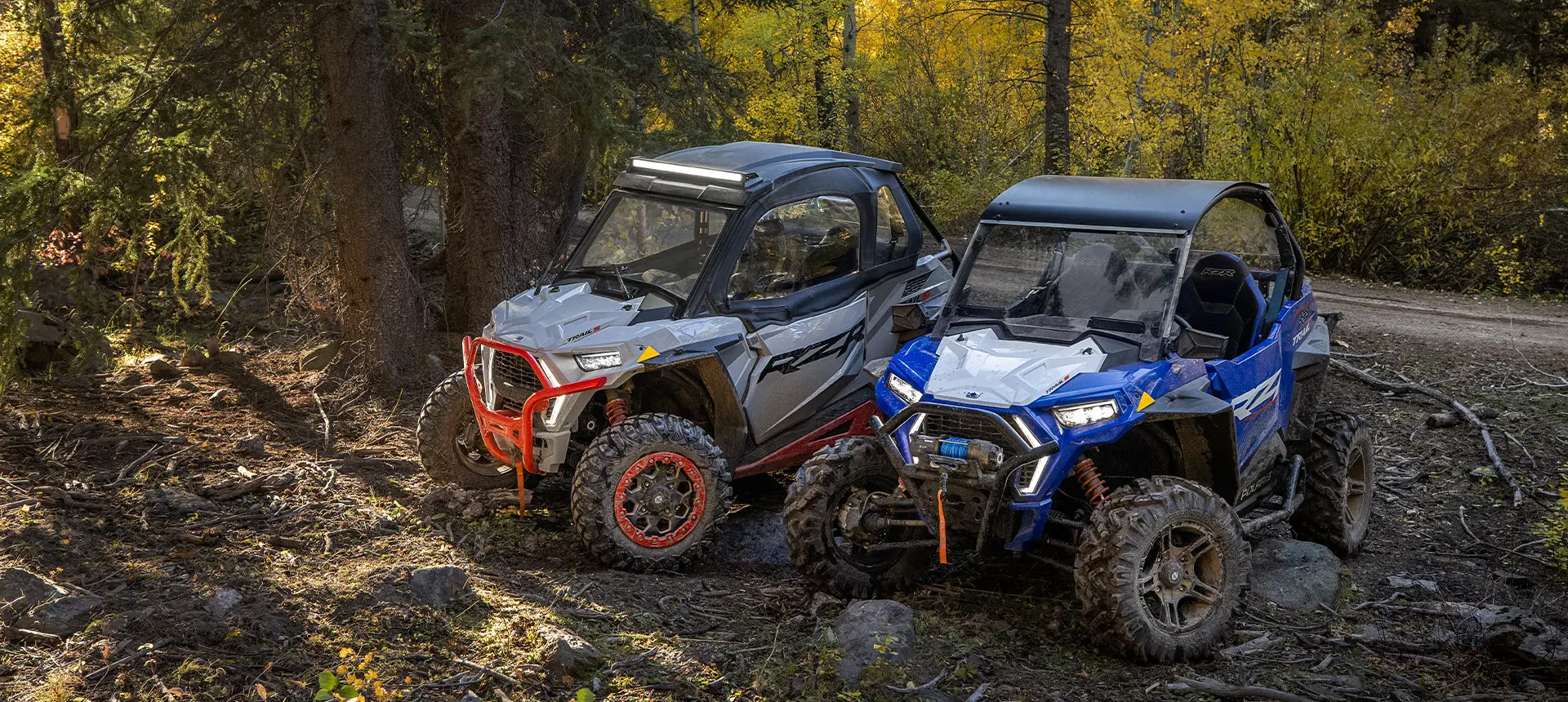 vista lateral de dos RZR estacionados en un sendero forestal