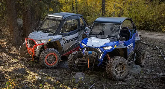 vue latérale de deux RZR stationnés sur un sentier forestier