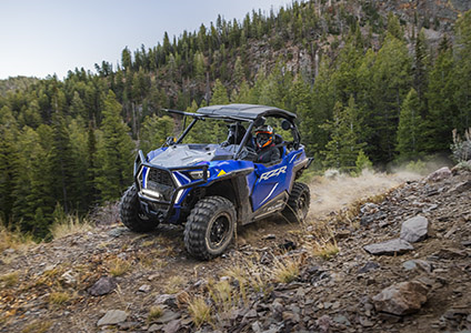 Polaris RZR Trail acelerando por un sendero rocoso con accesorios de la colección Explorer instalados