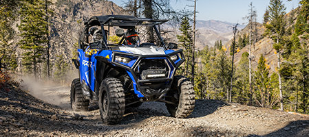 Front view of a RZR trail going up a rocky hill