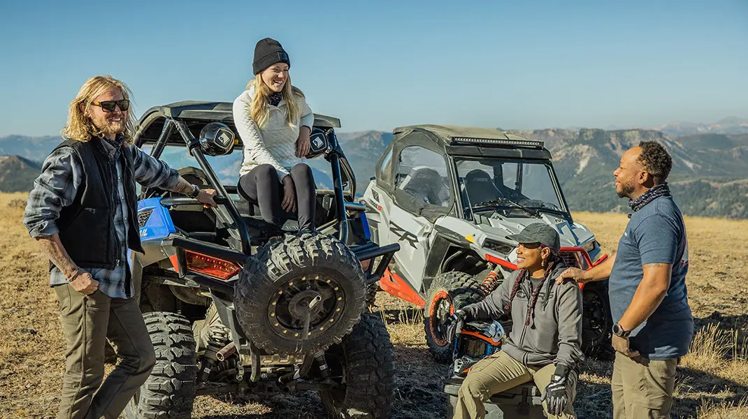 un groupe d’amis bavardAnt près de leur RZR, l’une des filles assises sur le coffre de son rzr
