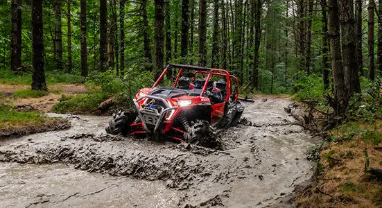 RZR XP 1000 High Lifter going through a muddy lake between a route.