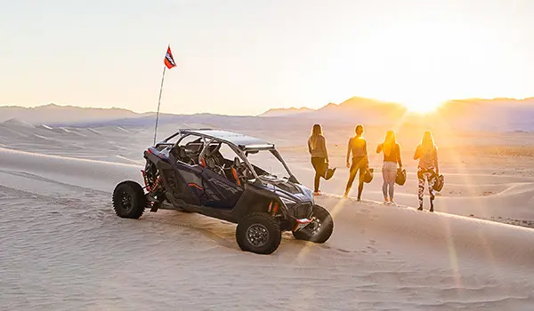 personas mirando fijamente al atardecer cerca de su polaris rzr pro r 4 side by side