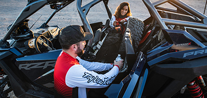 una pareja usando el almacenamiento de los asientos plegables en su polaris rzr pro r 4 side by side