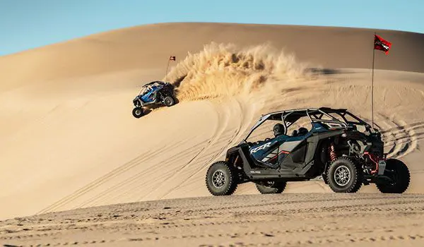 un polaris rzr pro r arremetiendo contra una duna con un polaris rzr pro r 4 esperando cerca