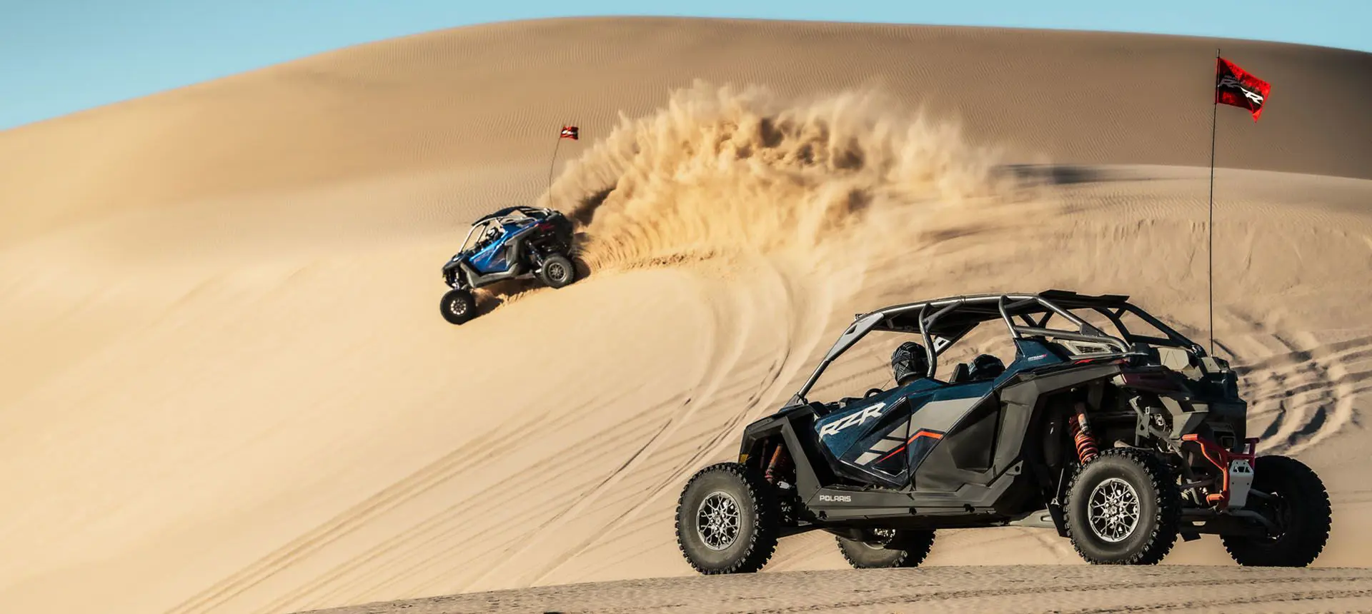 un polaris rzr pro r arremetiendo contra una duna con un polaris rzr pro r 4 esperando cerca