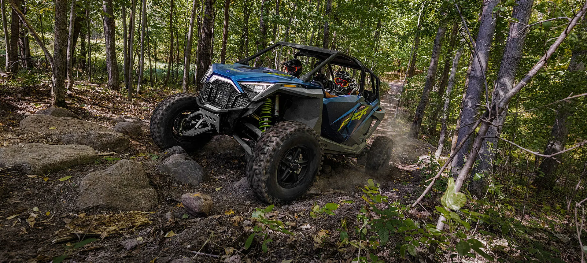 polaris rzr turbo r 4 side by side driving over a rough forest trail