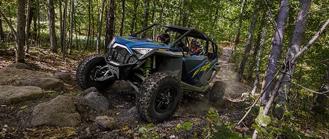 polaris rzr turbo r 4 side by side driving over a rough forest trail
