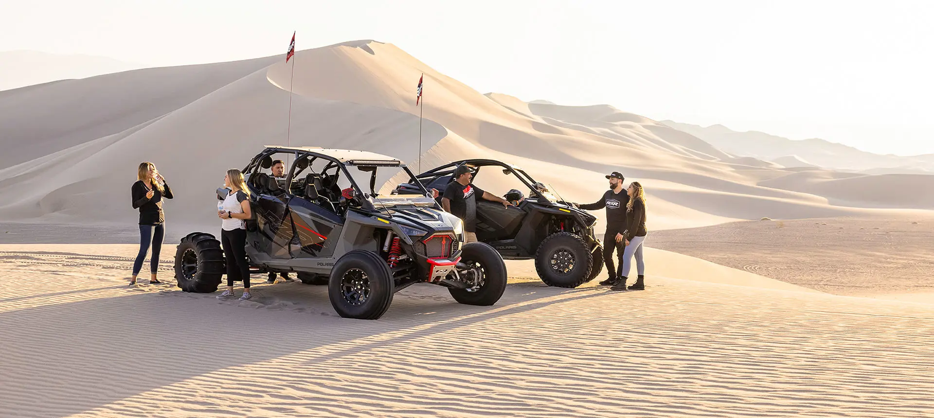people relaxing after a ride in their polaris rzr turbo r 4 side by sides in the desert