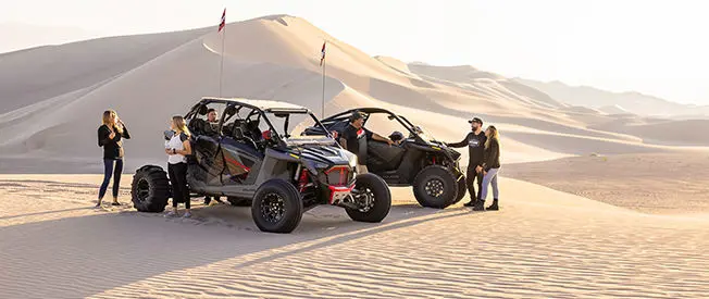 people relaxing after a ride in their polaris rzr turbo r 4 side by sides in the desert
