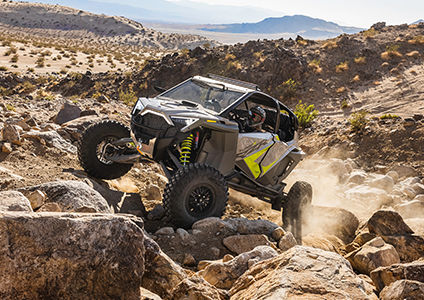 polaris rzr turbo r driving over rocky terrain with front and rear bumper accessories