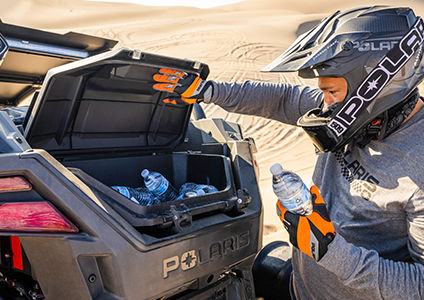 Rider taking a bottle of water out of the rear storage bin of a RZR Turbo R