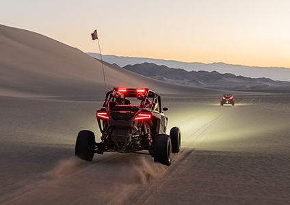 RZR Turbo R taillights shining with the dunes ahead illuminated by its headlights