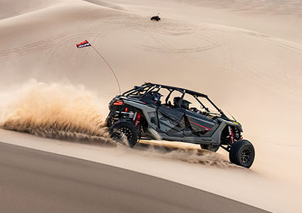 RZR Turbo R 4 with accessories from the Dune Collection speeding down a desert dune