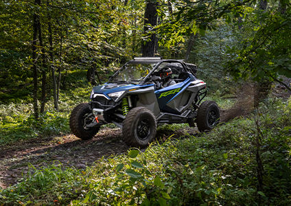 RZR Turbo R speeding down a heavily forested trail with accessories from the rugged trail collection