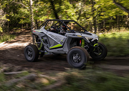 polaris rzr turbo r speeding through a forest trail
