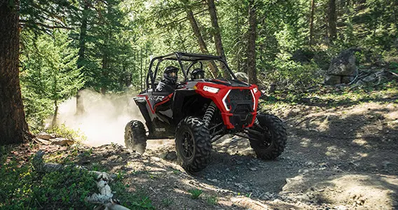 side-by-side rzr xp 1000 levantando polvo en un sendero forestal