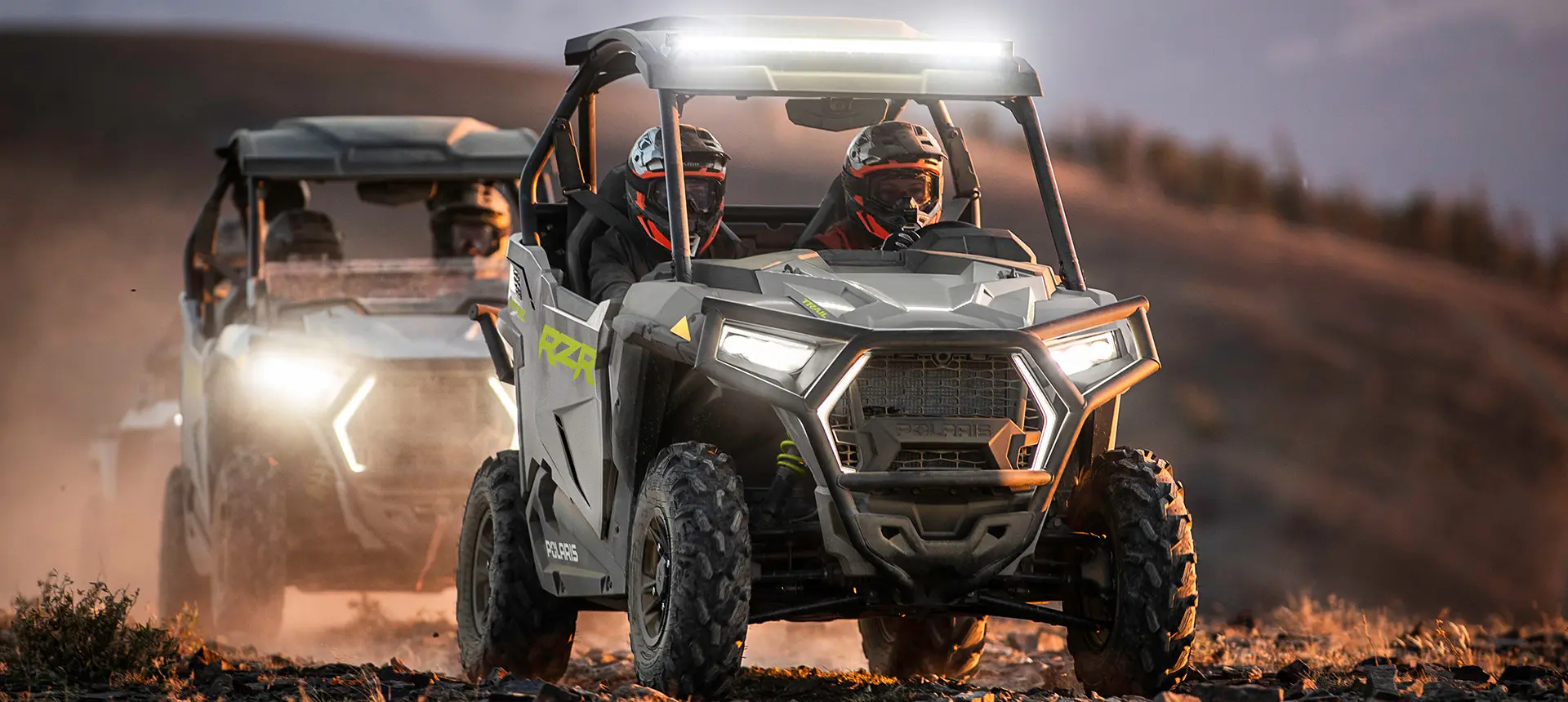 riders in a rzr trail side by side with headlights and light bar illuminated