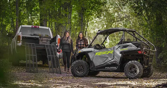 couple of women unloading a blue rzr trail side by side