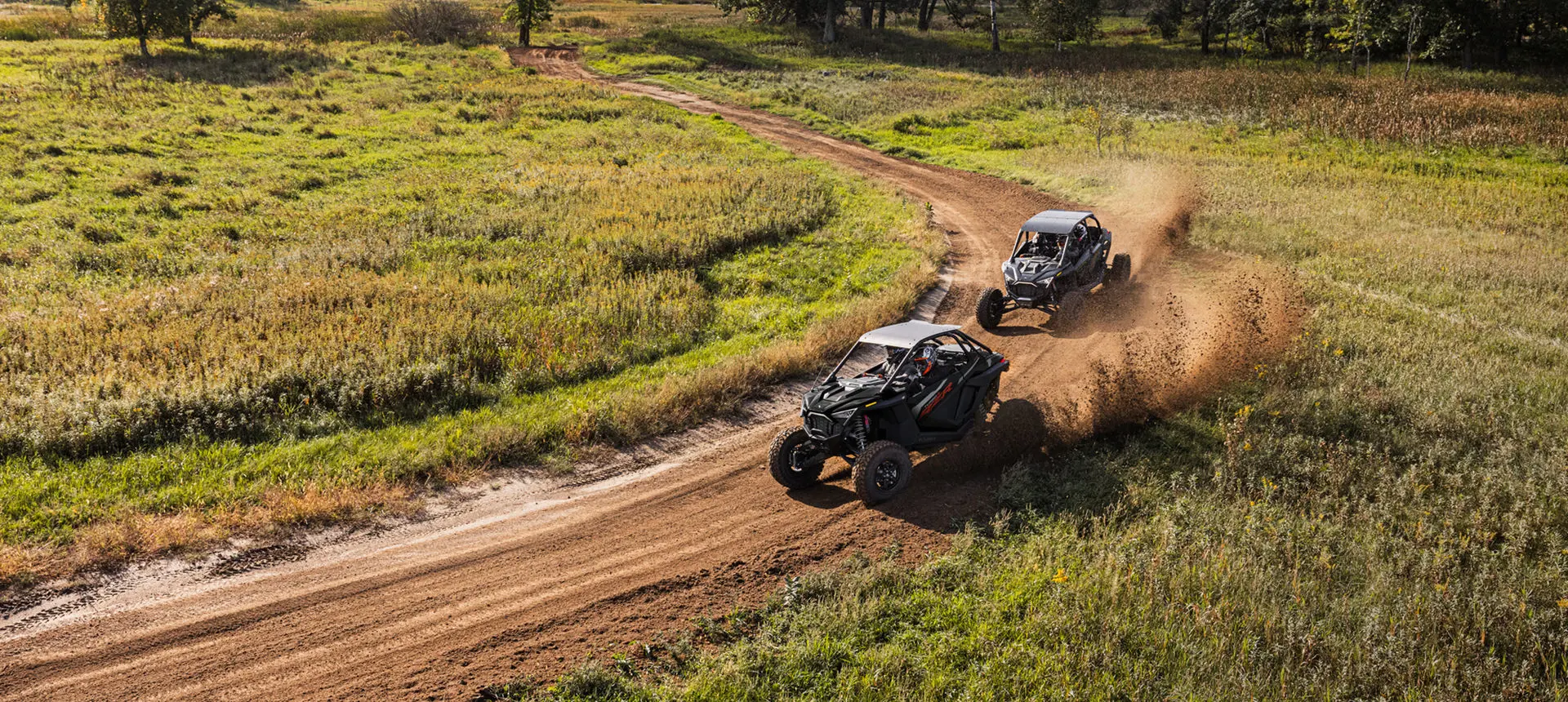 2 côte à côte RZR à ciel ouvert se poursuivant dans un virage serré