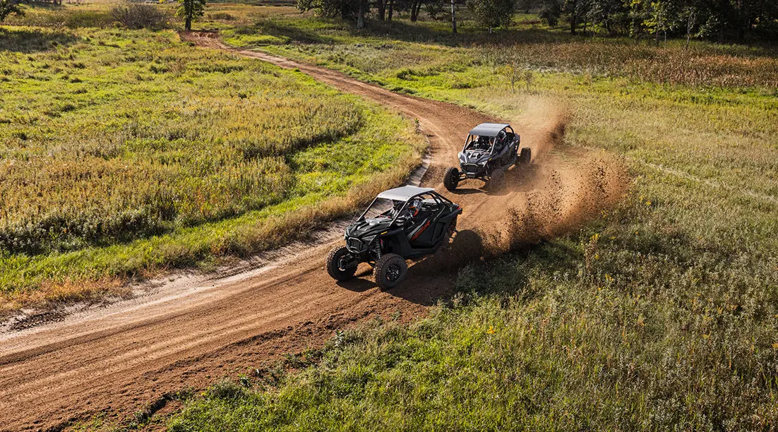 2 côte à côte RZR à ciel ouvert se poursuivant dans un virage serré
