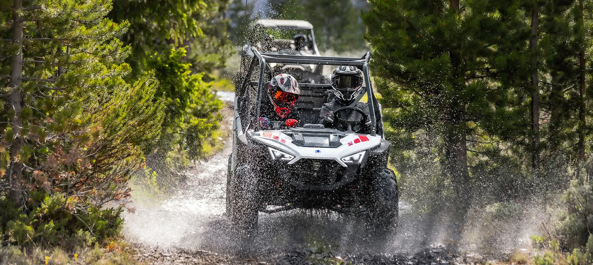 enfants traversant une flaque de boue dans un côte à côte RZR 200