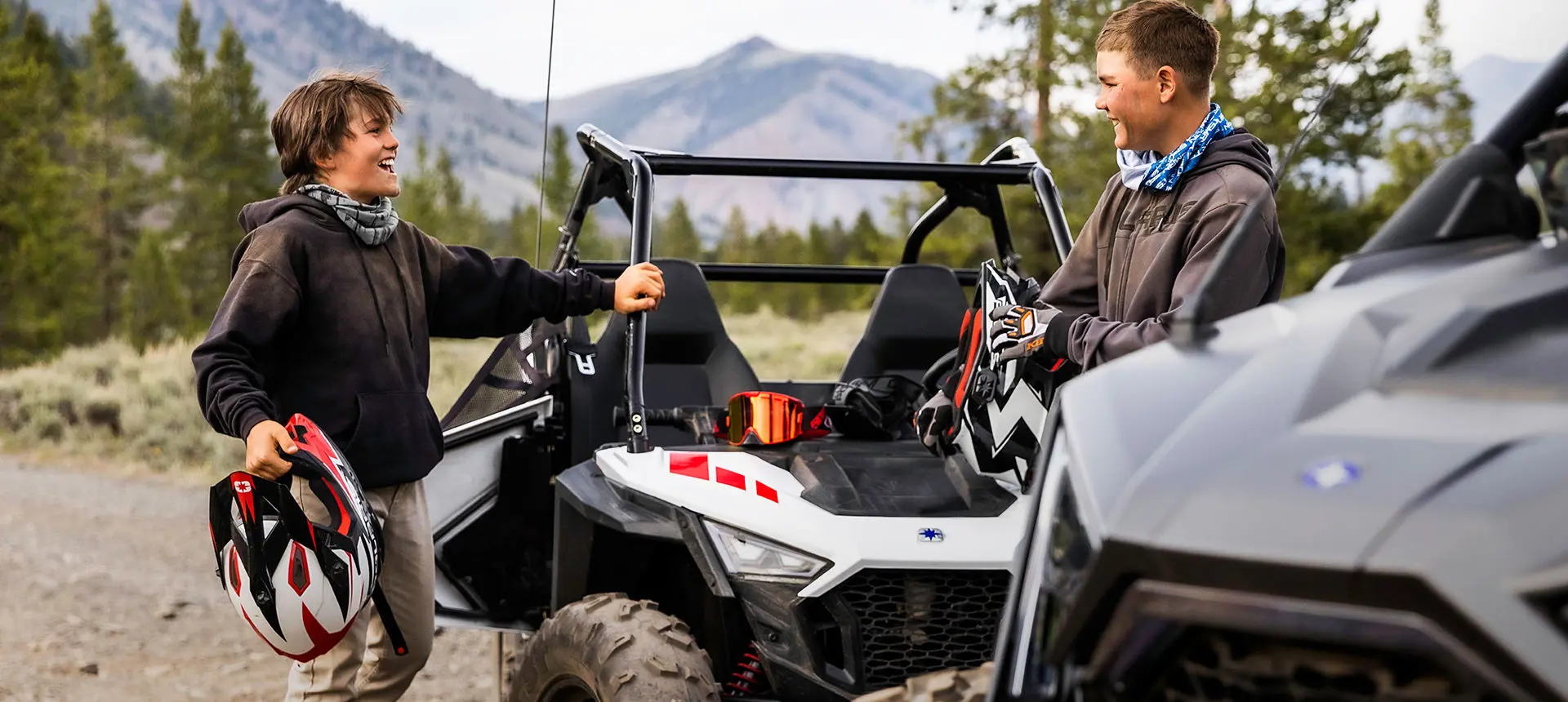 2 garçons souriant après avoir fait un tour dans un côte à côte rzr 200