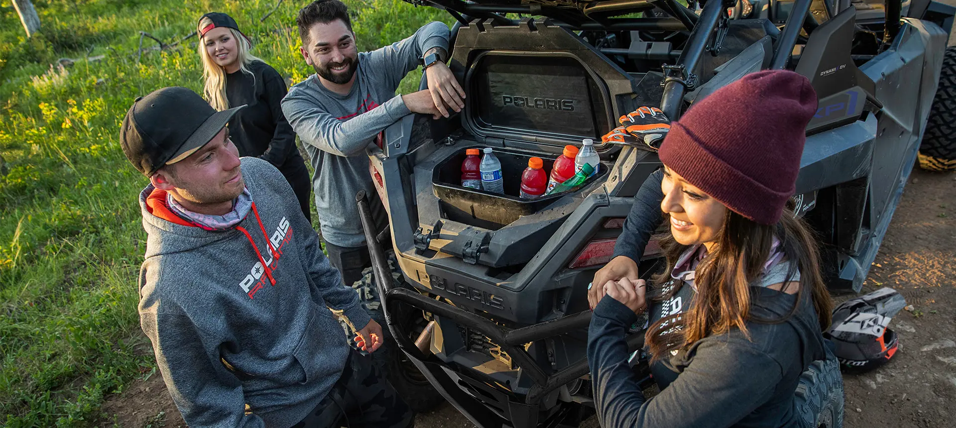 friends grabbing drinks from the cooler in their rzr pro xp 4 side by side