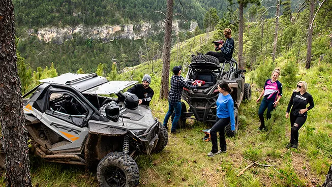 amis déchargeant de l’équipement après une randonnée et dans leur côte à côte rzr pro xp