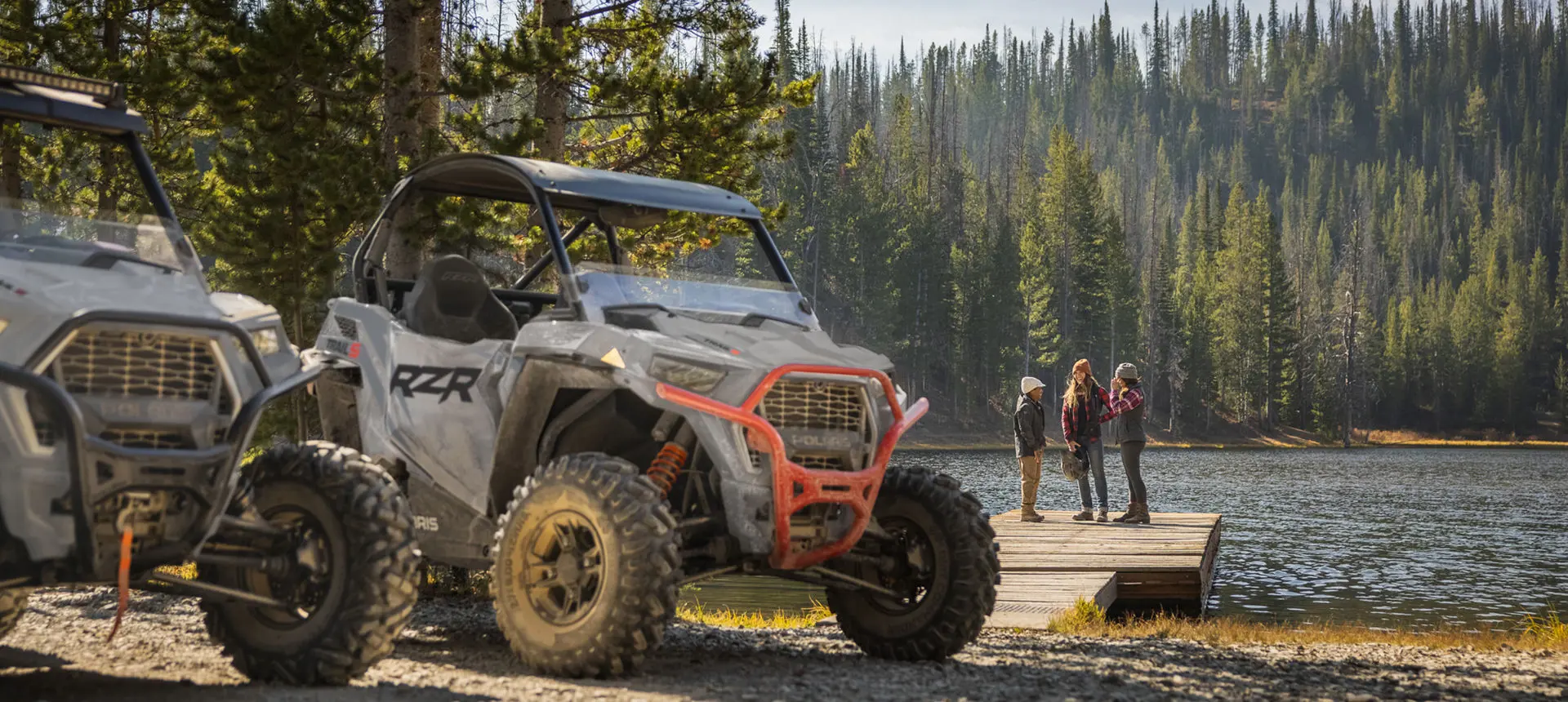 People standing on a dock near their RZR Trail S side by sides
