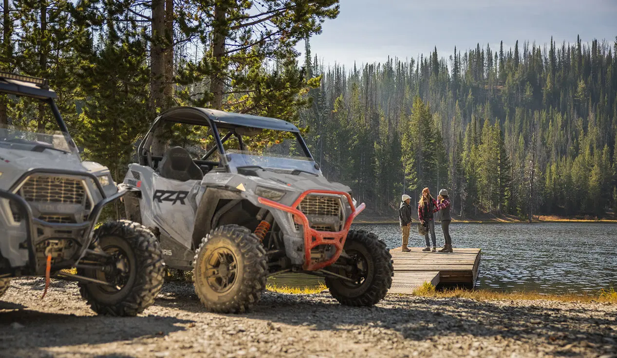 People standing on a dock near their RZR Trail S side by sides