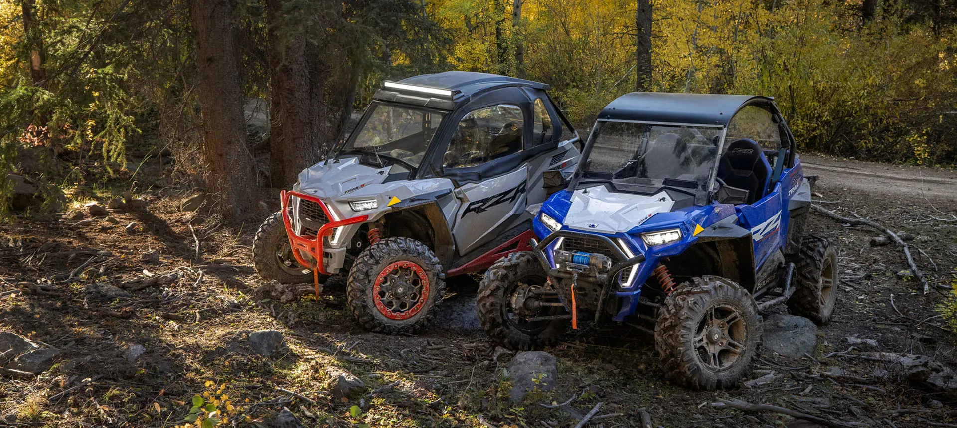 RZR Trail and Trail S side by sides parked near a trail