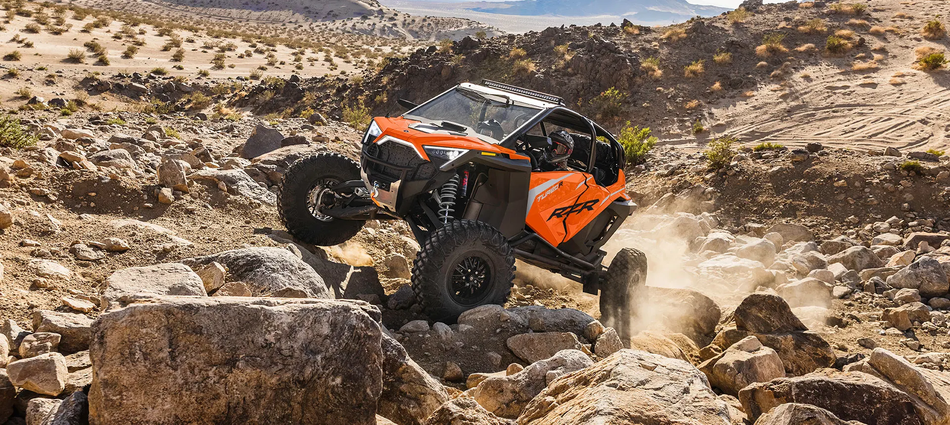 rzr turbo r 4 en naranja de locura ascendiendo por una colina rocosa