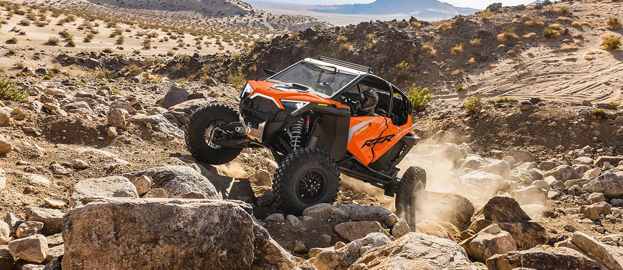 rzr turbo r 4 en naranja de locura ascendiendo por una colina rocosa
