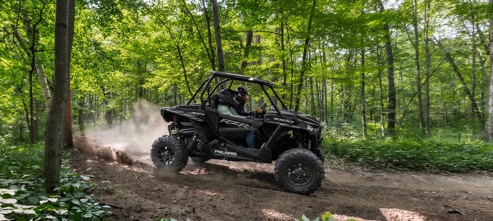RZR XP 1000 avec 2 personnes sur un sentier forestier