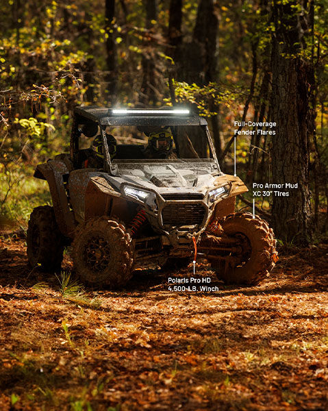 Rear Speaker Pods, Full-Coverage Fender Flares, Extreme Kick-Out Rock Sliders, and Polaris Pro HB 4500-pound Winch from the mud package installed on a storm gray 2025 Polaris RZR XP side by side.
