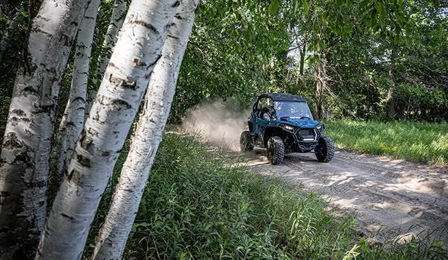 polaris rzr trail s side by side cruising down a forest trail