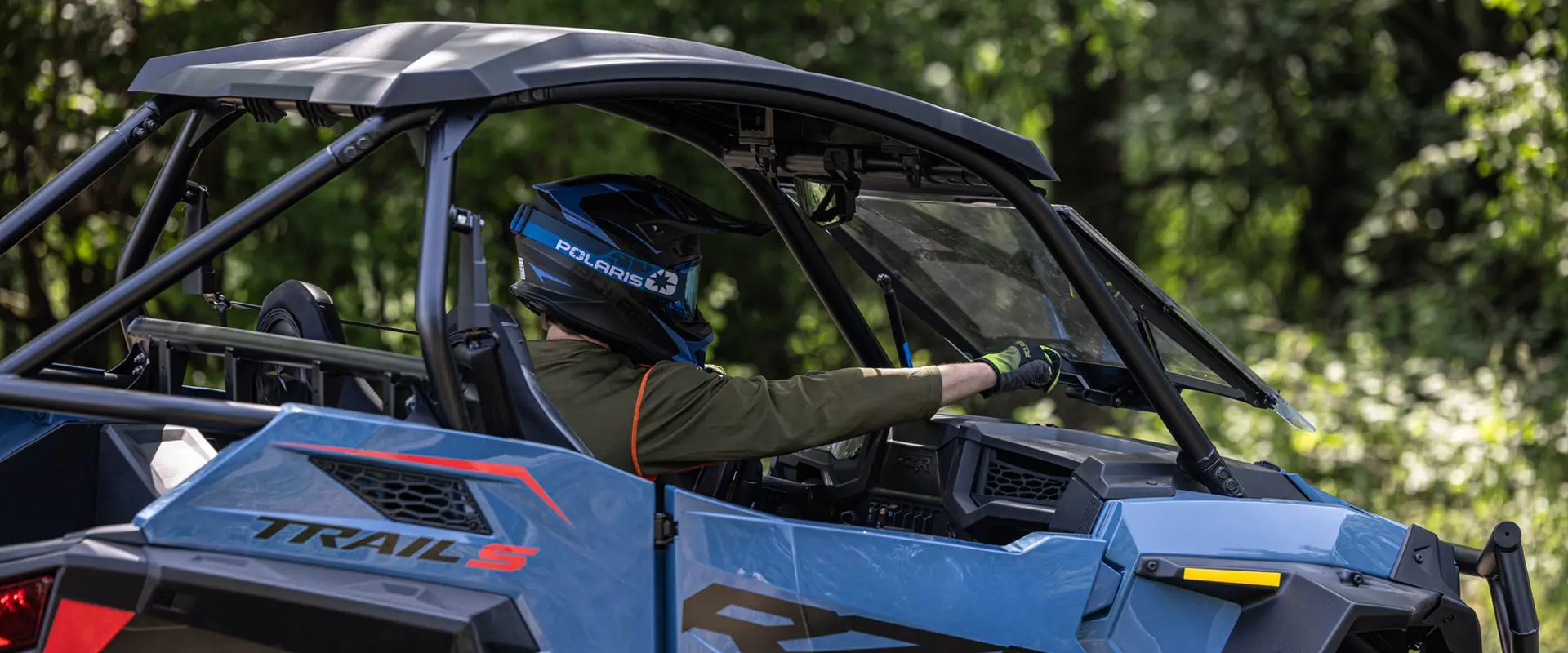 rider pushing out the tip out windshield on his polaris rzr trail s side by side