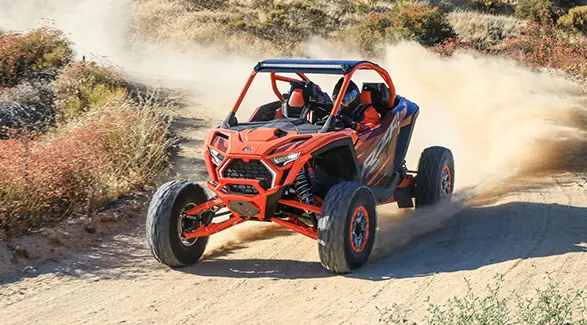Front view of a 2025 Polaris RZR Pro R Factory Armored Edition side-by-side driving through a desert.