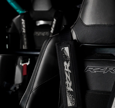 Close-up of the driver seat in a 2025 Polaris RZR Pro R side-by-side featuring enhanced contouring, seat heating and venting, and a new harness.