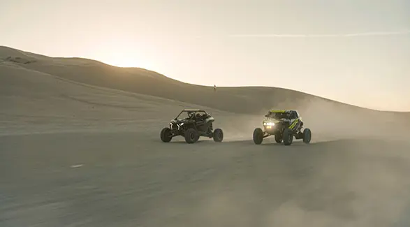 Two 2025 Polaris RZR Pro R side-by-sides driving near each other in the desert.