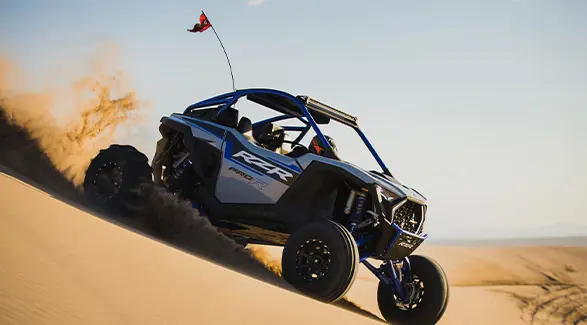2025 Polaris RZR Pro R side-by-side driving down a desert dune.