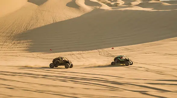Long-distance view of two 2025 Polaris RZR Pro R side-by-sides driving in the desert.