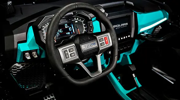 Steering wheel and dashboard inside a 2025 Polaris RZR Pro R side-by-side.