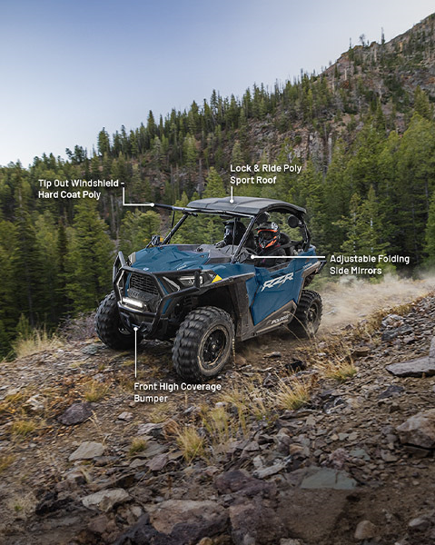 Tip-out hard-coat poly windshield, Lock & Ride poly sport roof, Adjustable folding side mirrors and front high coverage bumper accessories from the Explorer Package installed on a 2025 Polaris RZR Trail side-by-side.